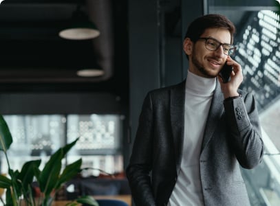 man leaning against window while talking on his phone