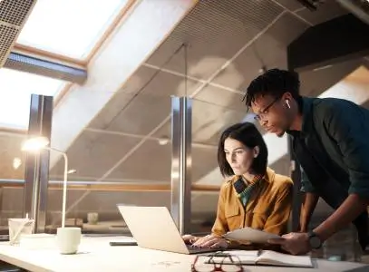two people working from a laptop and tablet in the office