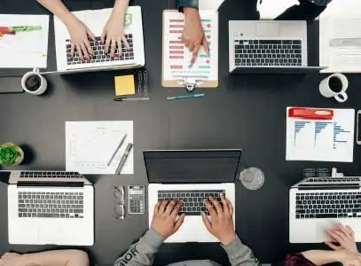 hands working on 6 laptops