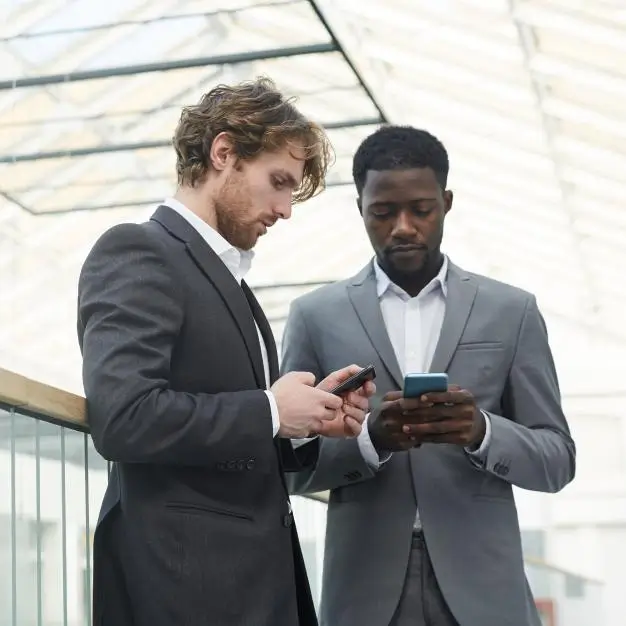 2 men on their phones standing next to each other