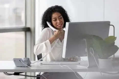 woman talking on phone while looking at laptop