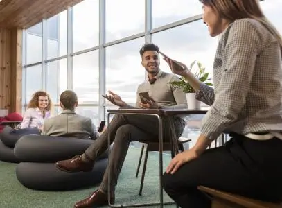 people in office, 2 people at desk holding their phones and talking