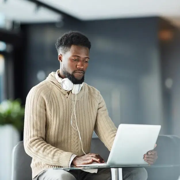 man with headphone around his neck working on his laptop