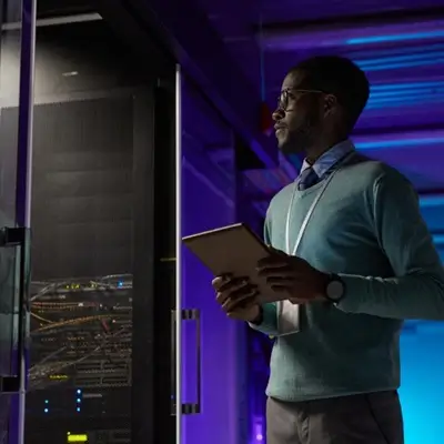 Man holding tablet looking into server room