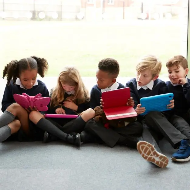 school children sitting together wach playing on a tablet