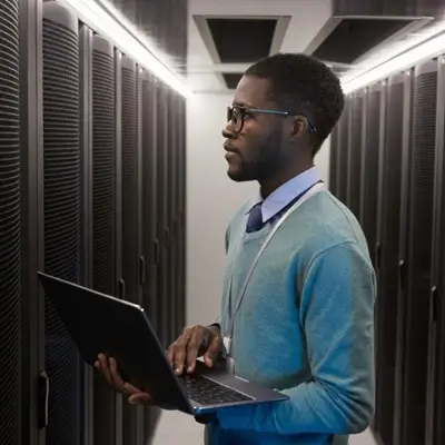 man working from laptop in a server room