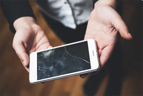 phone with a cracked screen in someone's hands