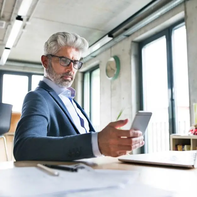 Male sitting at his desk looking at his phone