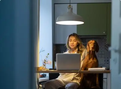 women sitting at table working from laptop with dog sitting next to them
