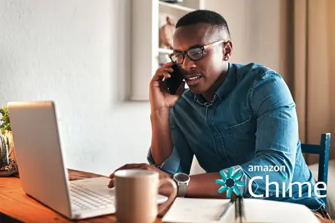 Man talking on the phone while looking at his laptop