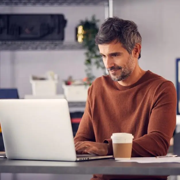 man sitting at desk working on his laptop 