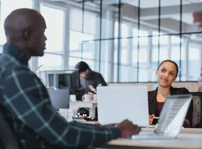 man and women talking at the their desks