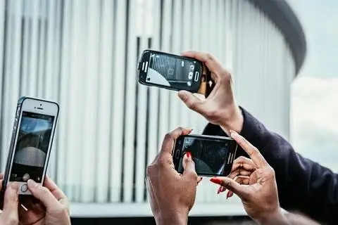 people's hands holding phones up to take photos