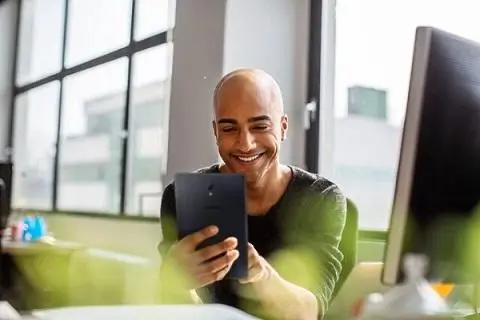 man sitting at his desk looking at his tablet