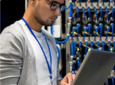 Man working from his laptop in a server room