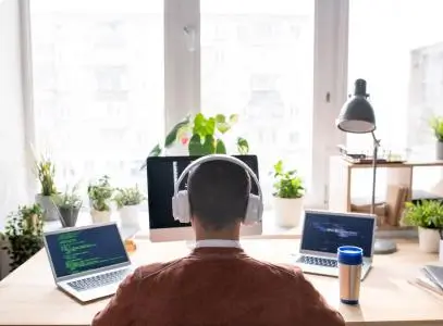 man working from multiple devices at desk