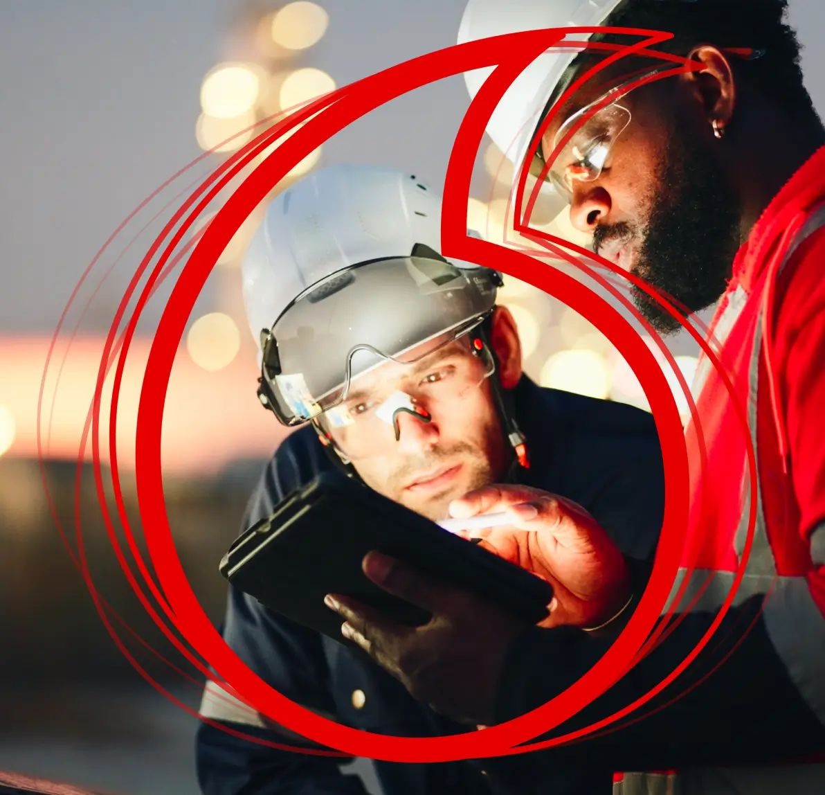 A smiling man wearing glasses works at a computer desk with code on the monitors, overlaid with a large red Vodafone logo.
