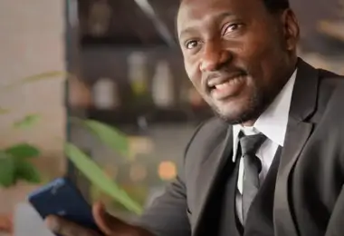 Smiling businessman holding a smartphone in an office setting