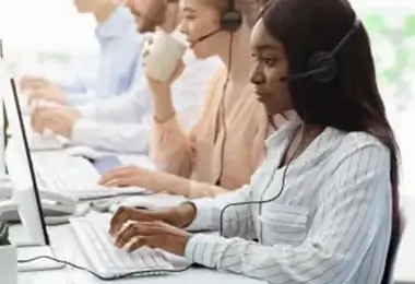 Customer support team wearing headsets and typing on computers in an office